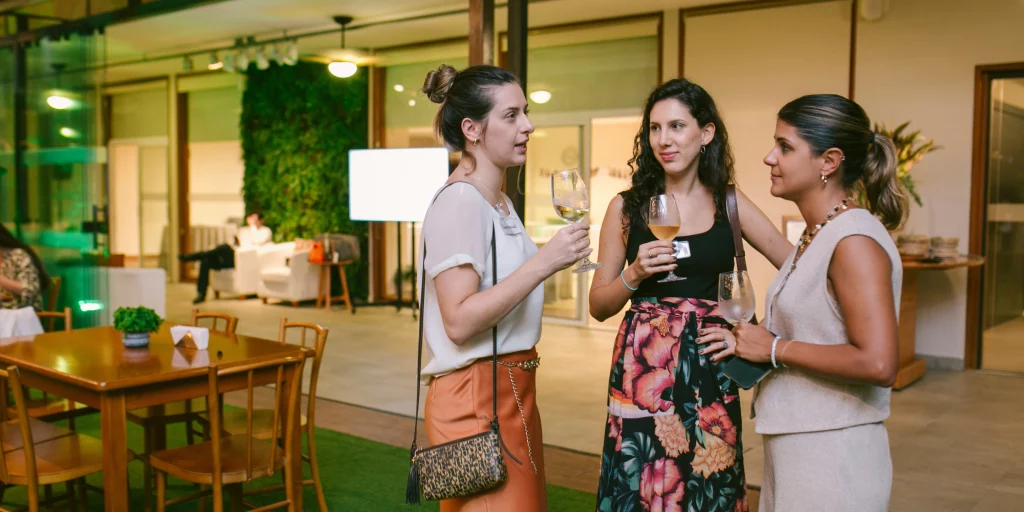 Três mulheres conversando enquanto tomam um drink a noite no jardim da Cosy Casa Mirante.