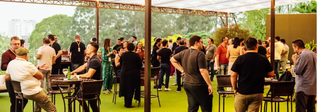 Foto do gramado coberto da Cosy Casa Mirante em um evento com várias pessoas conversando ao final do ano.